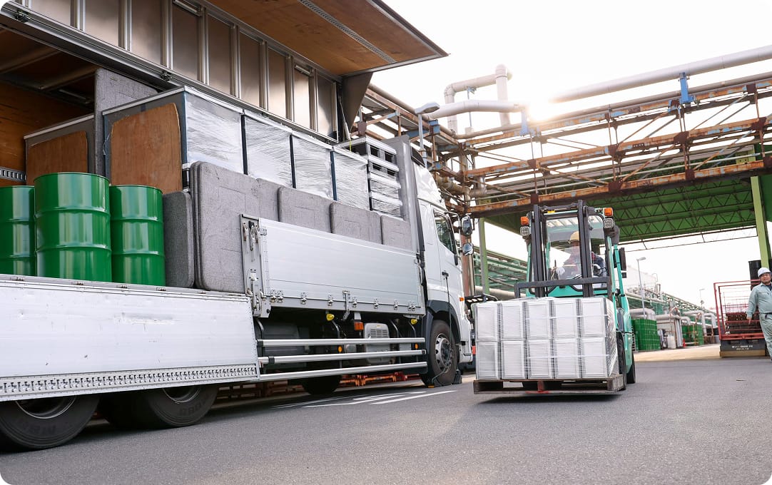 荷物を積載したトラックとフォークリフトが並んでいる写真