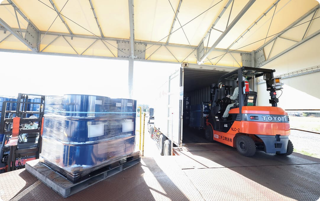 パレットに積まれた荷物と人が乗ったフォークリフトの写真