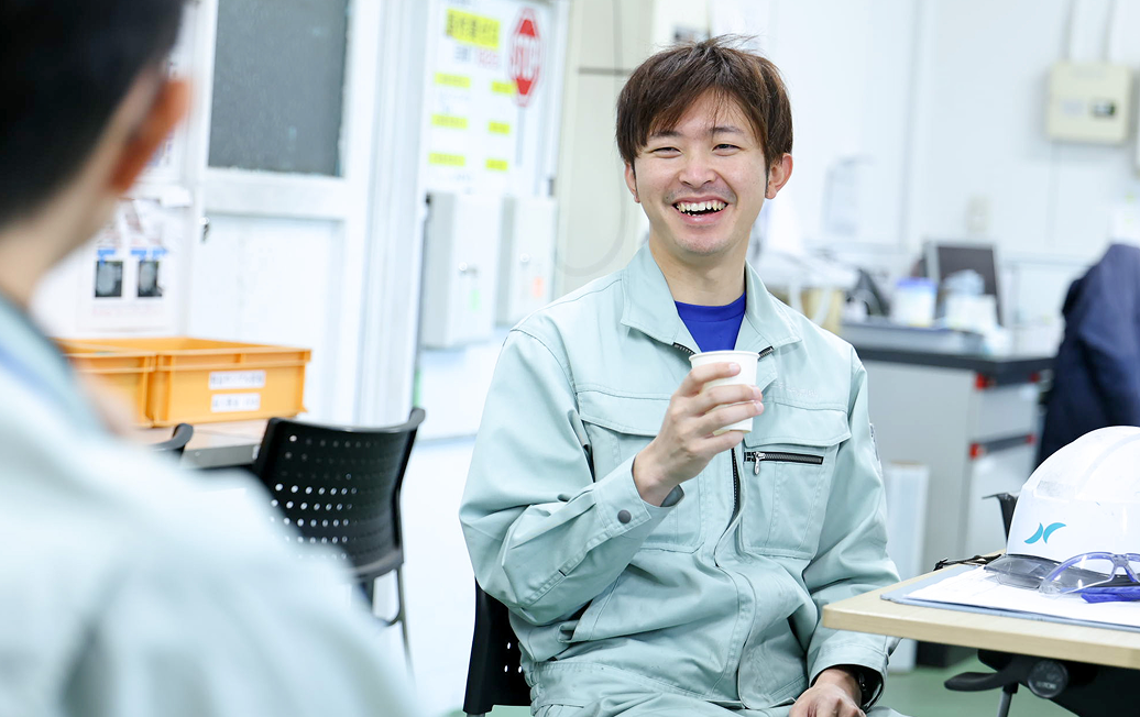 紙コップを手に仲間と談笑するA.Hさん